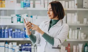 Farmaceutka w białym fartuchu analizuje skład leku, który może być wydany na receptę farmaceutyczną.
