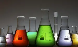 Kolorowe płyny w kolbach laboratoryjnych, od białego po żółty, zielony, pomarańczowy i fioletowy. Jedna z nich zawiera substancję przypominającą arszenik.