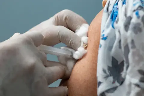 Ręka w rękawiczce medycznej podaje zastrzyk. To ważny krok w kierunku zakończenia pandemii, dzięki szczepieniom covid.