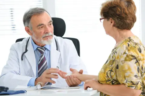Ordynator bada nadgarstek pacjentki, uważnie słuchając jej dolegliwości.