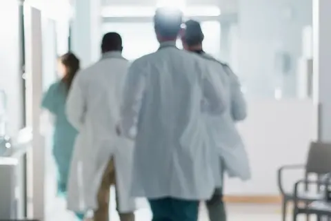 Lekarze w białych fartuchach spieszą korytarzem. Zastanawiasz się, ile zarabia lekarz?