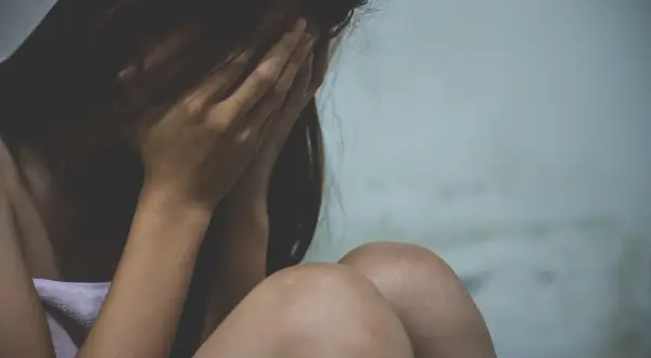 Kobieta ukrywa twarz w dłoniach, przygnębiona. Sytuacja przypomina wypowiedzenie umowy o pracę a zwolnienie lekarskie od psychiatry.