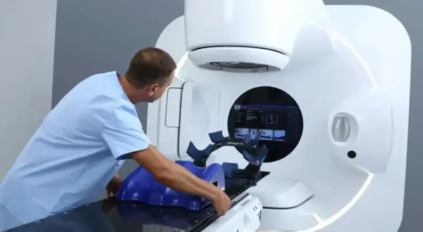 Medyk przygotowuje pacjenta do radioterapii na nowoczesnym urządzeniu Elekta.