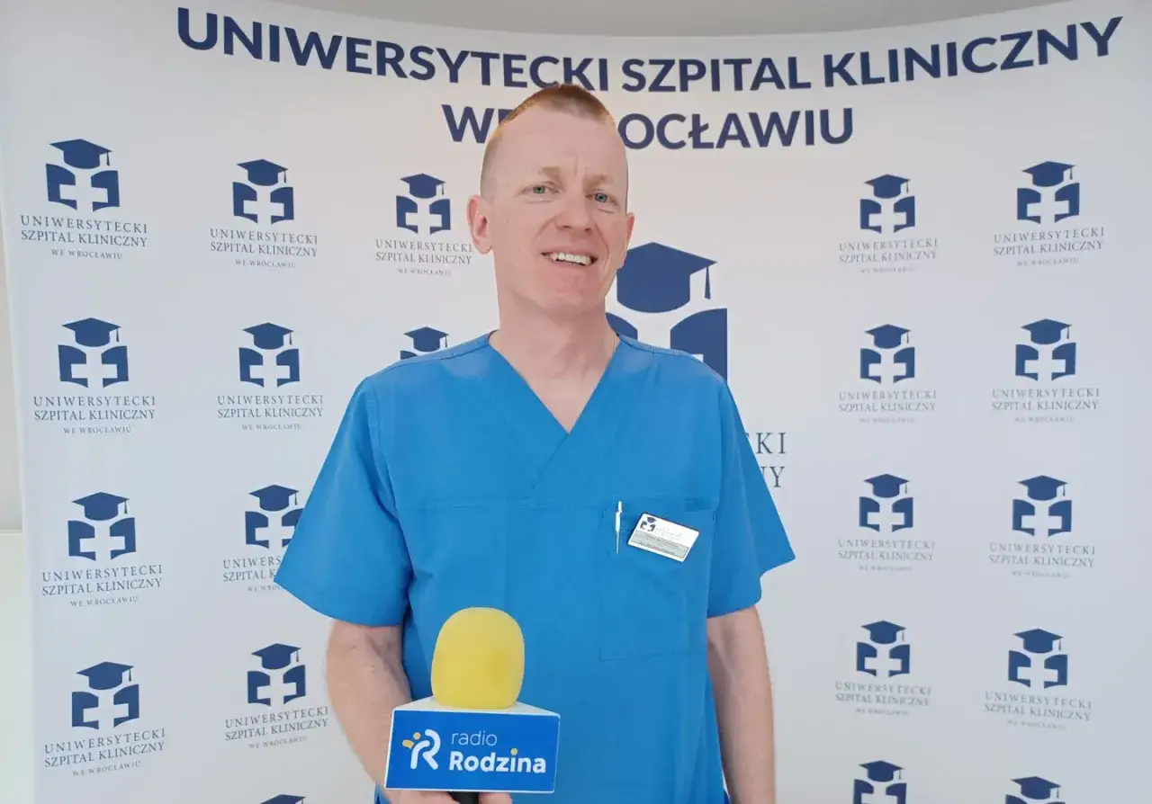 Ordynator szpitala klinicznego we Wrocławiu, ubrany w niebieski uniform, trzyma mikrofon radia Rodzina.