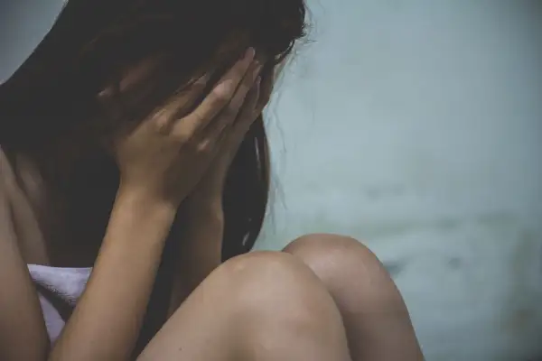Kobieta ukrywa twarz w dłoniach, przygnębiona. Sytuacja przypomina wypowiedzenie umowy o pracę a zwolnienie lekarskie od psychiatry.