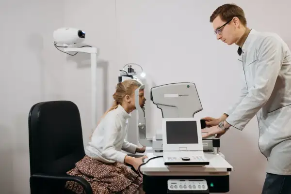 Okulista bada wzrok dziewczynki. Czy do okulisty potrzebne jest skierowanie? Zwykle nie, ale warto sprawdzić.
