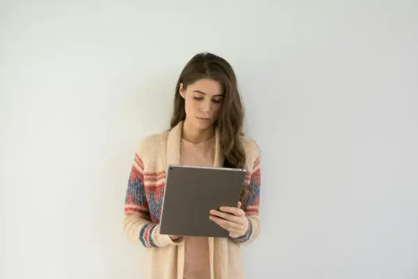 Kobieta w swetrze z kolorowym wzorem korzysta z tabletu, szukając informacji o l4 od psychiatry online.